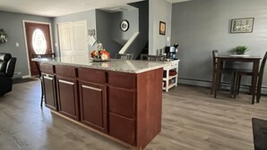 A kitchen with a central island, wooden cabinets, and a dining area with a table and chairs.