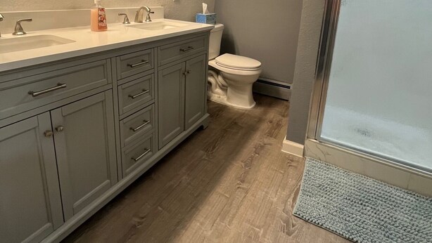 A bathroom with a large vanity, a toilet, and a shower area.
