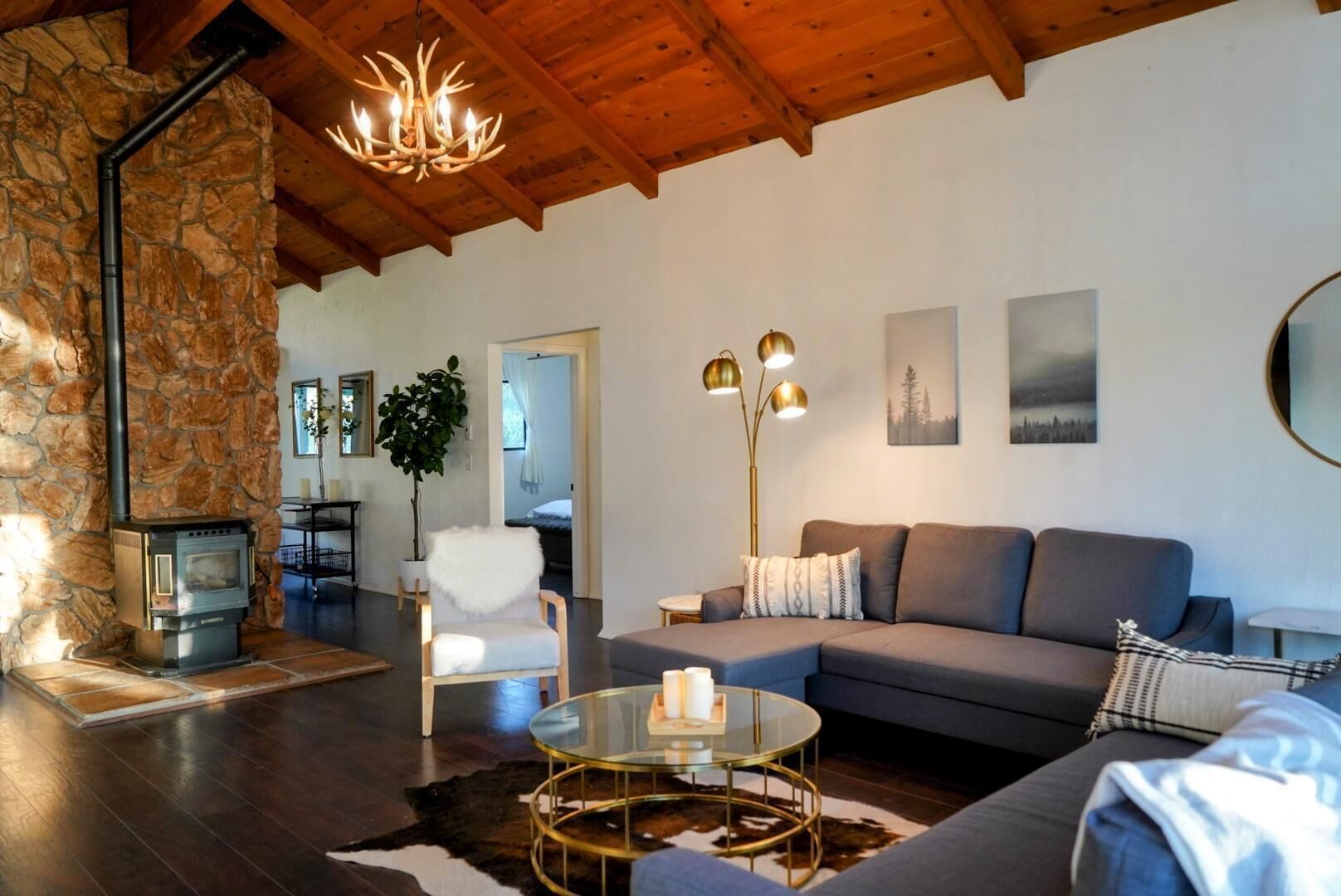 A cozy living room with a stone wall, a fireplace, a sofa, a coffee table, and a large mirror.