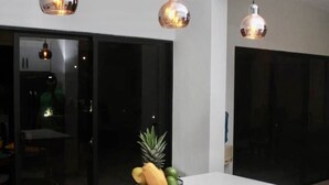 A modern kitchen with white cabinetry, a central island with a fruit bowl, and pendant lighting.