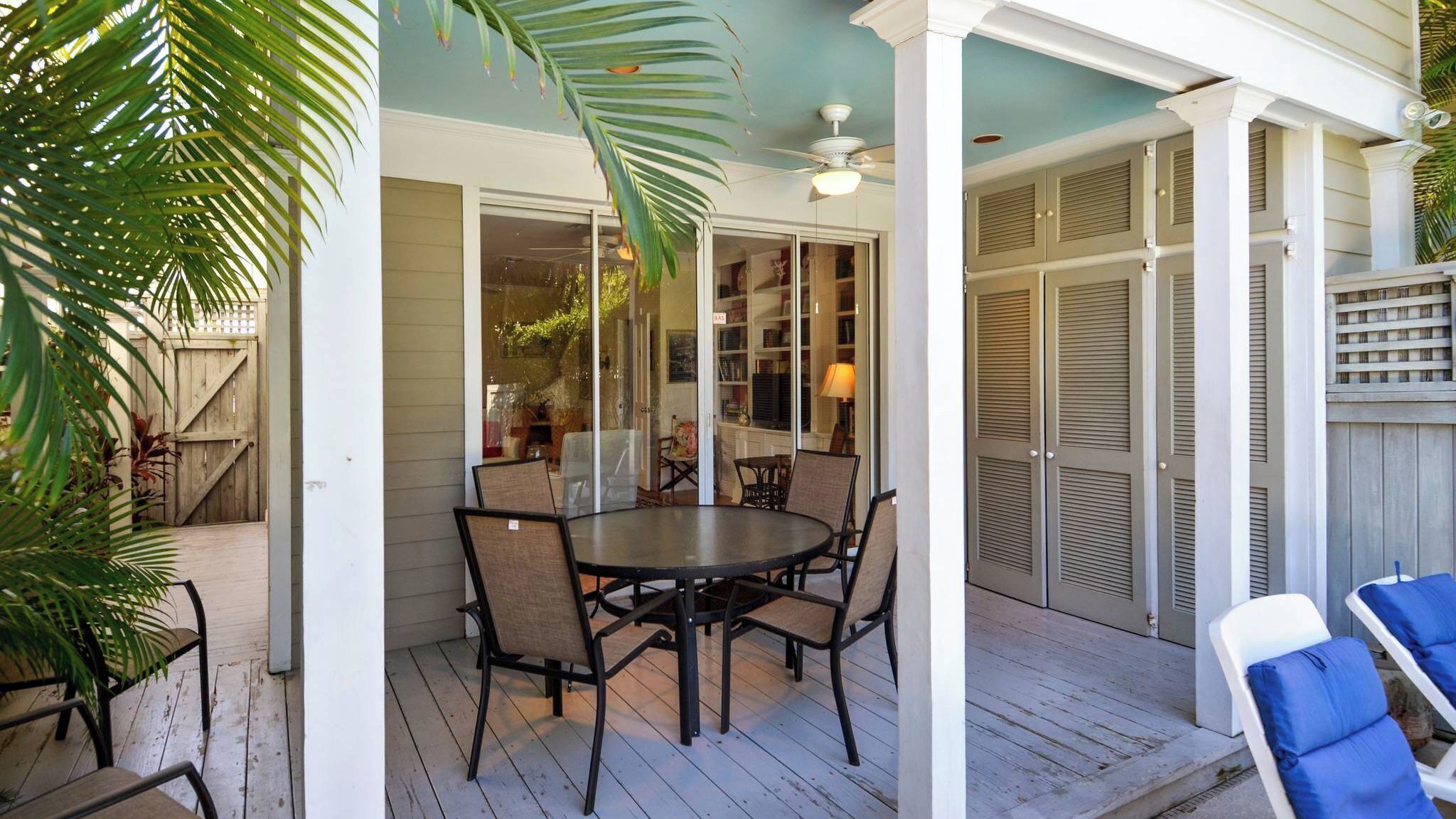 A covered patio with a table and chairs, a ceiling fan, and a view into the house.
