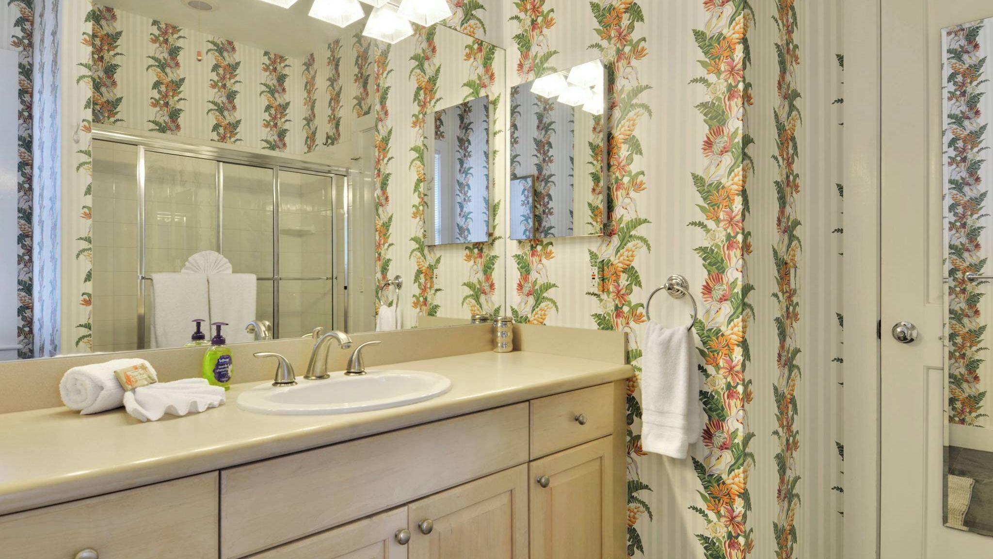 Une salle de bain avec un grand miroir, un lavabo et une douche.