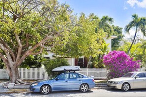 Stroll through a charming neighborhood with lush greenery and a picturesque home with a red door.