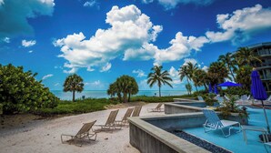 A resort pool area with lounge chairs, a pool, palm trees, and a clear view of the ocean. - Atlantic Paradise by Avantstay Great Location w/ Balcony, Outdoor Dining & Shared Pool & Hot Tub! (Key West)