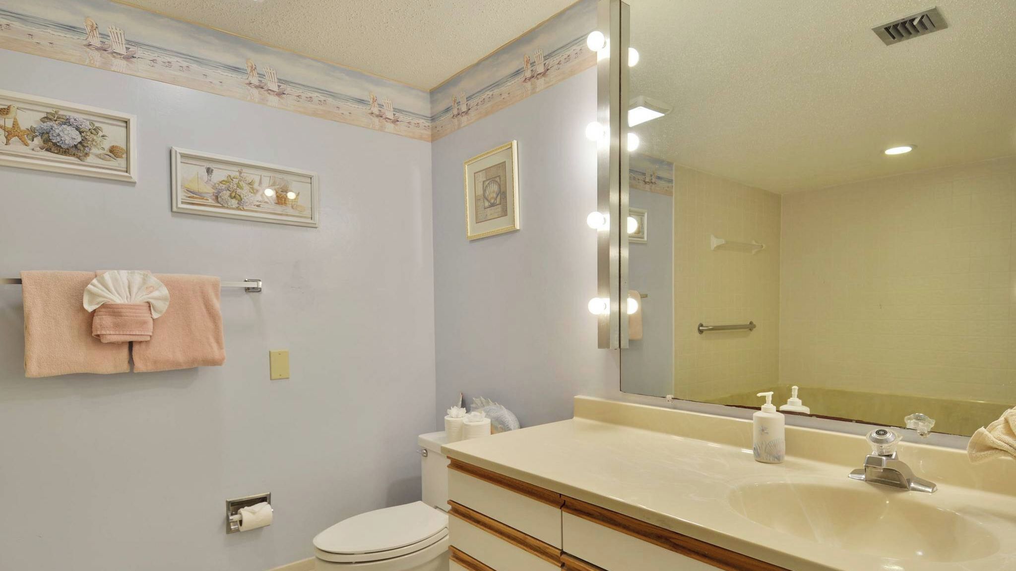 Une salle de bain équipée de toilettes, d’un lavabo, d’un miroir et d’un porte-serviettes.