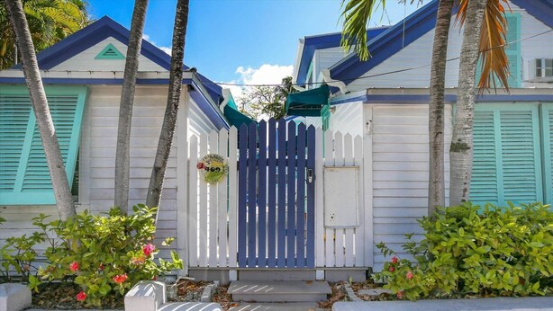 A house with a blue gate, white walls, and green shutters. - Windchime by Avantstay Walk to Duval Street Month Long Stays Only (Key West)