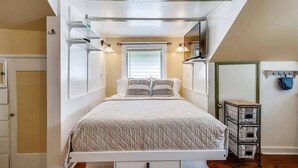 A bedroom with a bed, bedside lamps, a window, and a storage cart. - Windchime by Avantstay Walk to Duval Street Month Long Stays Only (Key West)