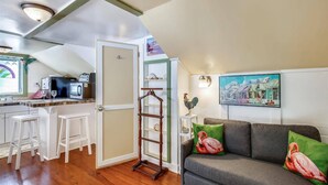 A cozy living room with a grey sofa, a wooden ladder, and a painting of a town scene. - Windchime by Avantstay Walk to Duval Street Month Long Stays Only (Key West)