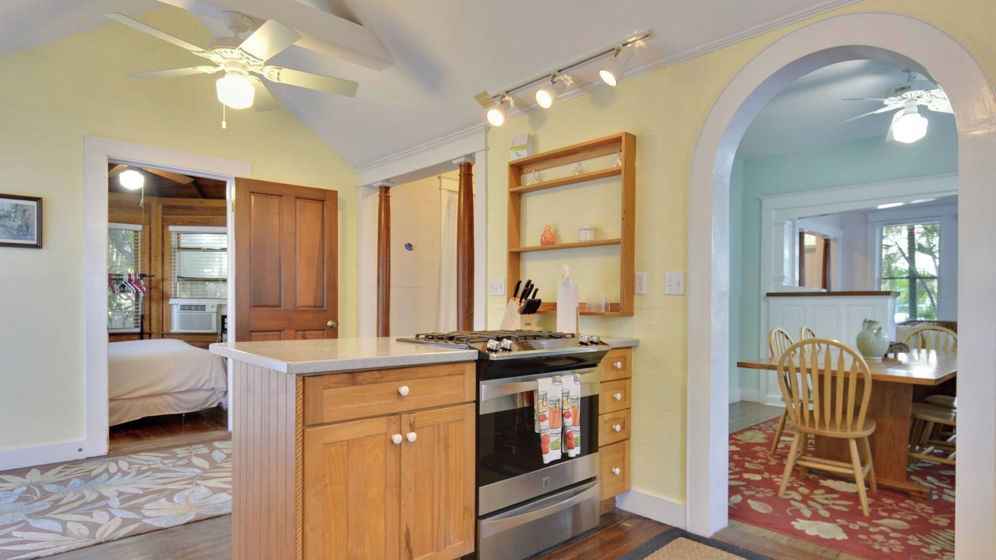 A kitchen with wooden cabinets, a built-in oven, and a dining area with chairs.