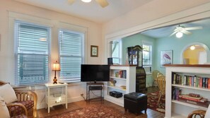 A living room with a television, bookshelf, and a large mirror.