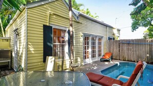A single-story house with a pool, a patio with a table and chairs, and a wooden fence. - Key Lime Pie by Avantstay Ideal Location w/ Splash Pool & Out Door Dining Month Long Stays Only (Key West)