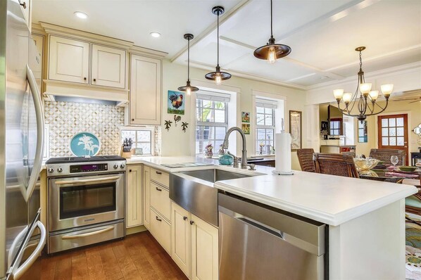 A kitchen with stainless steel appliances, a large island, and pendant lighting.