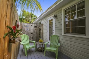 Relax in this serene outdoor space with two Adirondack chairs and a small table.