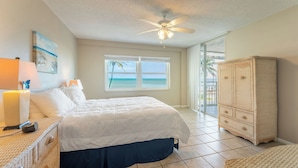 A bedroom with a bed, a ceiling fan, a window with a view of the ocean, and a wicker cabinet. - Brisa Del Mar by Avantstay Communal Pool Gated Community Ocean Front (Key West)
