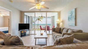 A spacious living area with a flat-screen TV, a ceiling fan, and a balcony with a view of the ocean. - Brisa Del Mar by Avantstay Communal Pool Gated Community Ocean Front (Key West)