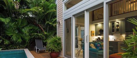 A poolside area with a sliding glass door leading to a kitchen and living area.