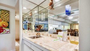 Une salle de bain moderne avec un grand miroir, un lavabo et un comptoir recouvert de carreaux.