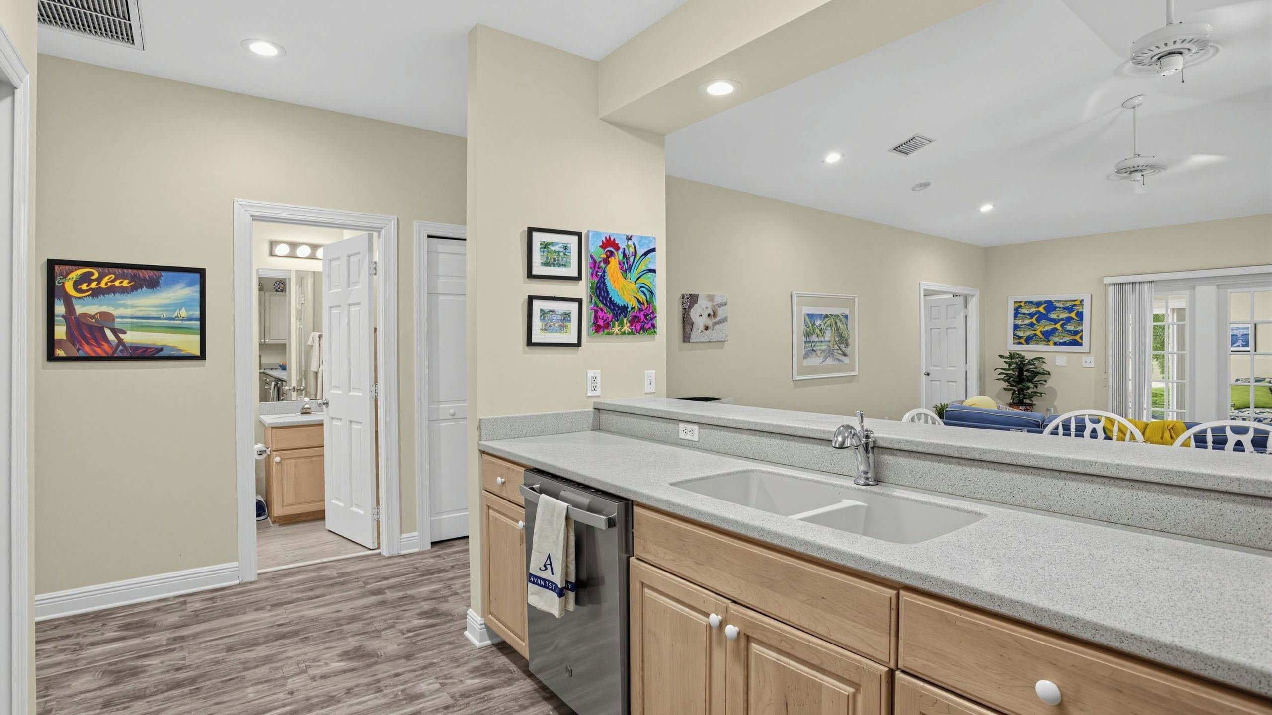 A modern kitchen with a double sink, wooden cabinets, and a view into the adjacent bathroom.