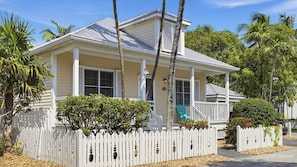 A single-story house with a porch, white picket fence, and a mailbox.