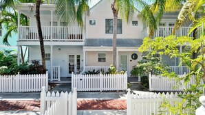 A two-story house with a white picket fence, a porch, and a small garden. - Breezy Bungalow by Avantstay Close 2 Zachary Taylor State Park w/ Shared Pool Month-long Stays (Key West)
