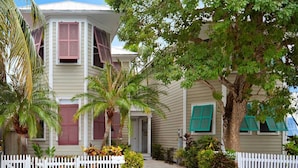 A two-story house with a white picket fence, a front porch, and a tree in the yard. - Amelia Home by Avantstay In Historic Old Town w/ Pool (Key West)