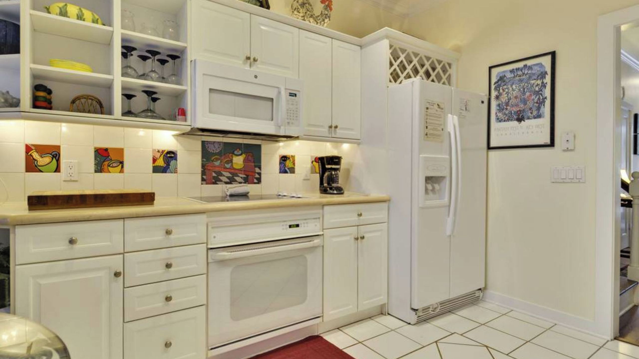 A kitchen with white cabinets, a microwave, a refrigerator, and a coffee maker.