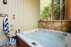 A hot tub with a stone wall backdrop and a wooden bench. - Scarlett by Avantstay Spacious Mountain Home w/ Gorgeous Views & Hot Tub (Park City)