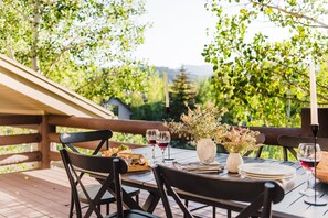 An outdoor dining area with wooden tables and chairs, surrounded by greenery and a wooden fence. - Scarlett by Avantstay Spacious Mountain Home w/ Gorgeous Views & Hot Tub (Park City)