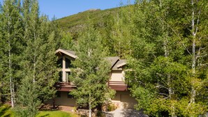A two-story building with a balcony, surrounded by dense forest and a clear sky.