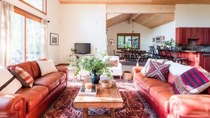 A spacious living room with leather sofas, a wooden coffee table, and a large window.