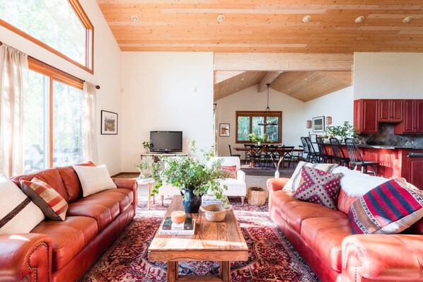 A spacious living room with leather sofas, a wooden coffee table, and a large window. - Scarlett by Avantstay Spacious Mountain Home w/ Gorgeous Views & Hot Tub (Park City)