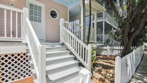 A two-story house with a white front porch, a wooden staircase, and a number '69' sign.