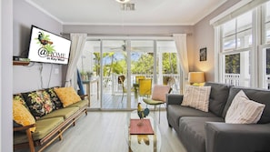 A living room with a sofa, a coffee table, and a couch. There is a television mounted on the wall. - Bogey's Retreat by Avantstay Golfer's Retreat w/ Shared Pool! Month Long Stays Only (Key West)