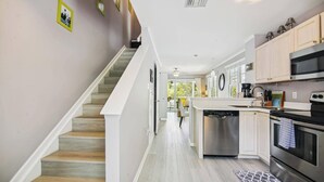 A kitchen with a central island, stainless steel appliances, and a staircase leading to another level.