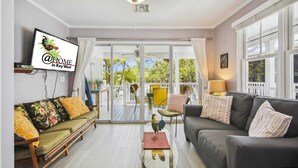 A spacious living room with a sofa, a coffee table, and a television mounted on the wall.