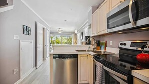 A modern kitchen with stainless steel appliances, a dishwasher, and a red kettle.