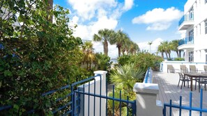 Un balcon d’hôtel avec vue sur la mer, entouré de verdure et de palmiers.