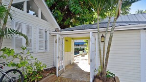 Une maison avec un patio couvert, un vélo et un petit jardin.