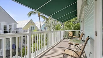 A covered porch with a table and chairs, white railings, and a green canopy.