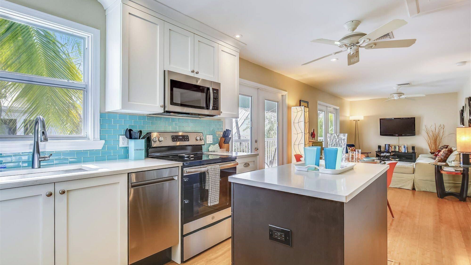 A modern kitchen with stainless steel appliances, a large island, and a dining area with a TV.