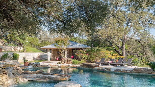 A pool area with stone features, lounge chairs, and a gazebo. - 10,000 Sq.Ft Lux Estate on 650 Acres with Amazing Pool, Spa & Hill Country Views (Marble Falls)