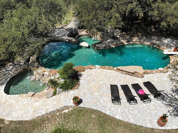 A pool with a stone deck and lounge chairs.