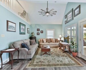 Relax in this stylish living room with two sofas, a coffee table, and side table, surrounded by framed artwork and a potted plant.