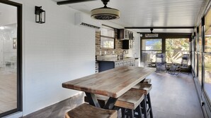 A modern kitchen with a large wooden table and bar stools, white brick walls, and large windows. - Coastal Heated Pool Home, 10 mins to the beach and downtown  (St. Augustine)