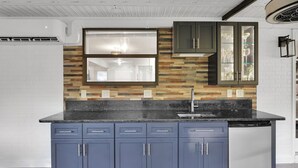 A modern kitchen with a black countertop, blue cabinets, and a built-in dishwasher. - Coastal Heated Pool Home, 10 mins to the beach and downtown  (St. Augustine)