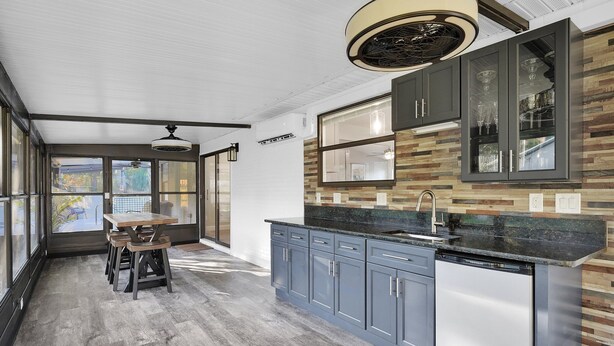 A modern kitchen with a built-in dishwasher, grey cabinets, and a wooden dining table with chairs. - Coastal Heated Pool Home, 10 mins to the beach and downtown  (St. Augustine)
