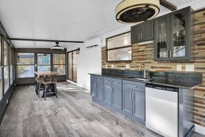 Una cocina moderna con lavavajillas integrado, armarios grises y una mesa de comedor de madera con sillas.