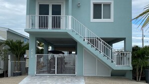 A two-story house with a balcony, a garage, and a staircase leading to the upper floor. - Beautiful home in Calusa, Key Largo (Key Largo)