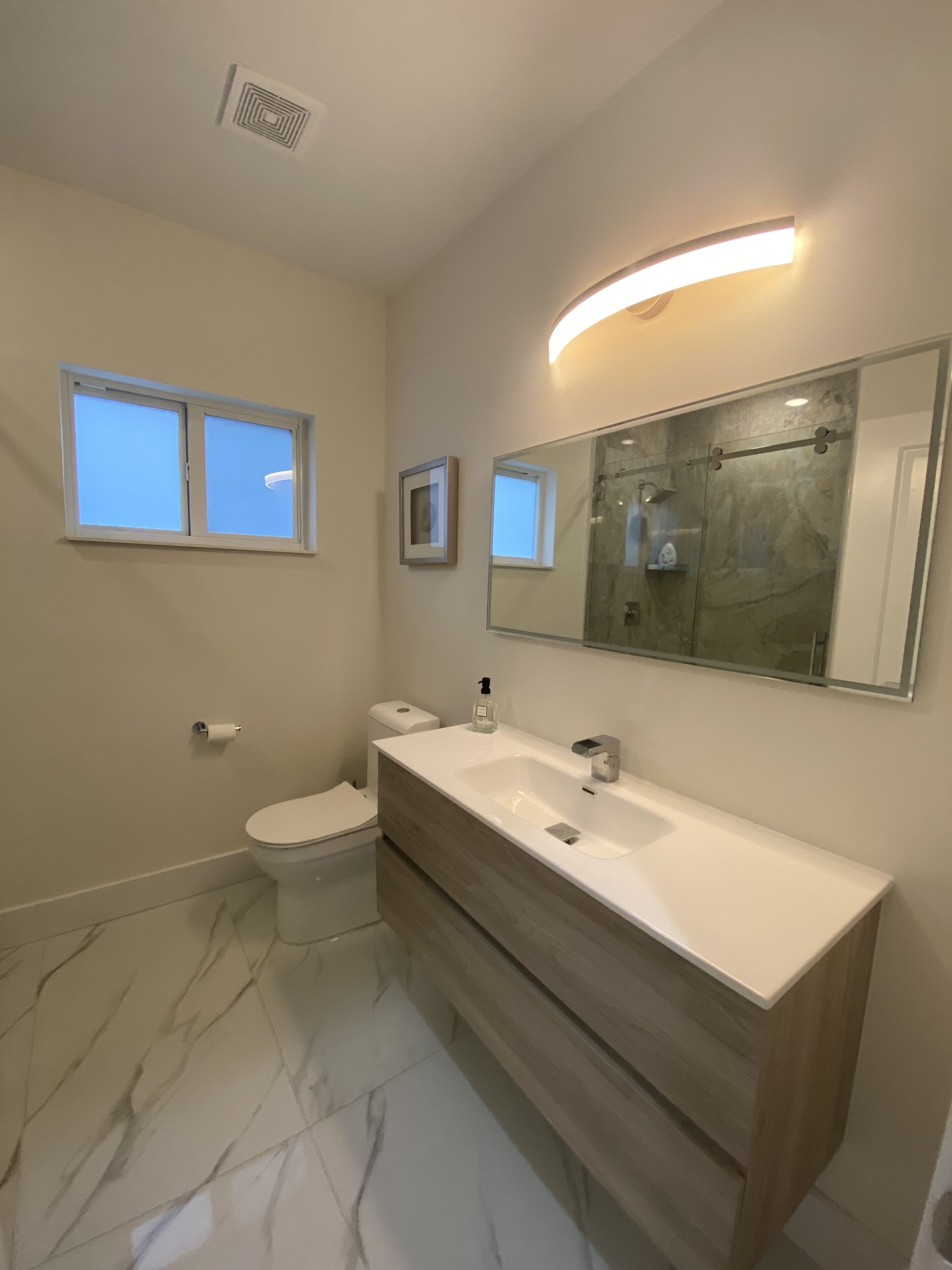 Ein modernes Badezimmer mit Toilette, Bidet, Waschtisch mit Spiegel und Dusche.