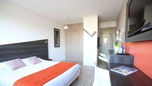 Et moderne hotelværelse med seng, skrivebord og fjernsyn.